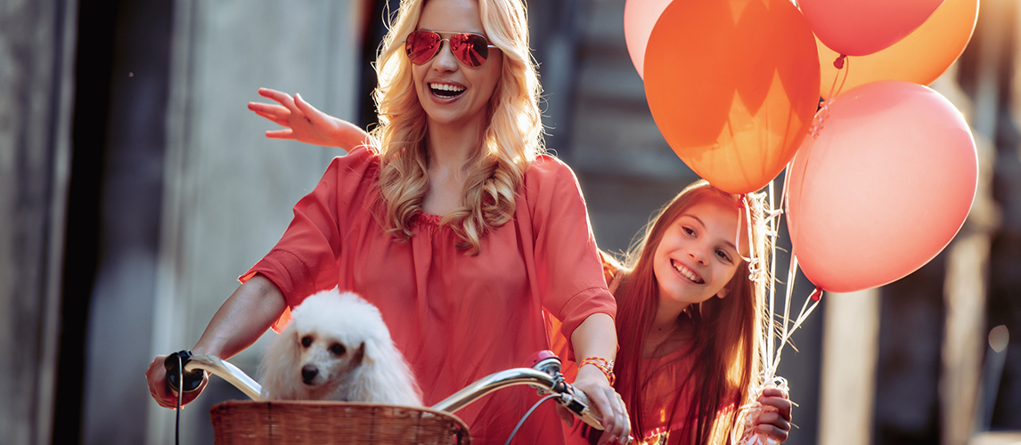 Beautiful mother and daughter riding bike with puddle in bas