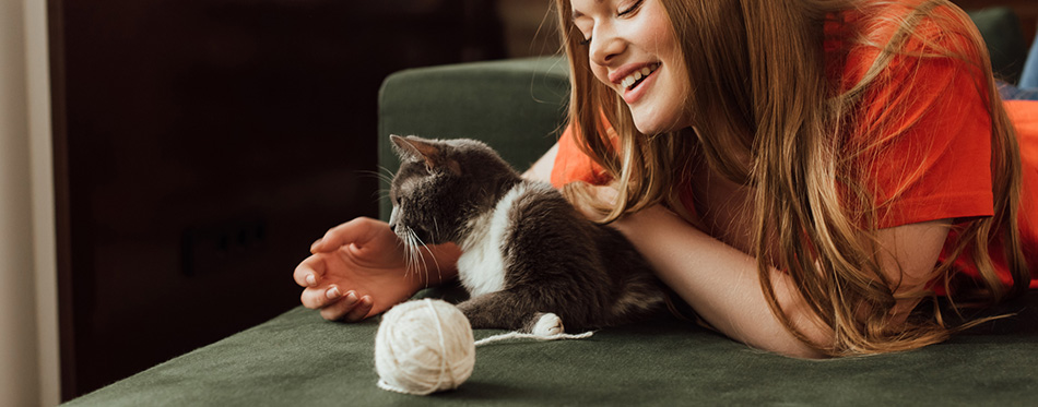 Cheerful girl playing cute cat near ball