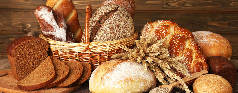 Different bread with ears and sunflower seeds on wooden backgro