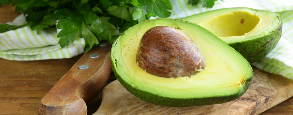 Ripe avocado cut in half on a wooden table