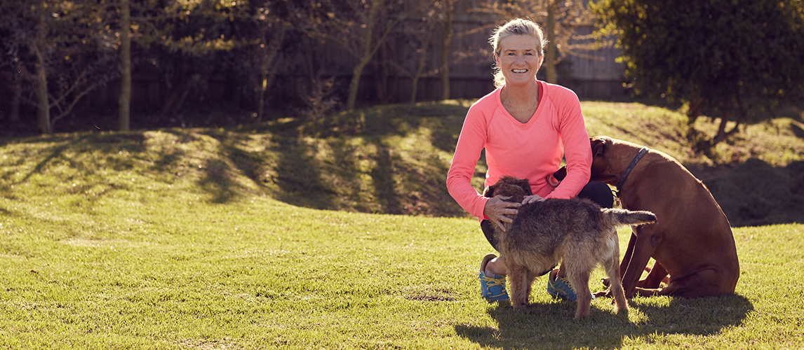 Senior woman petting dogs in garden