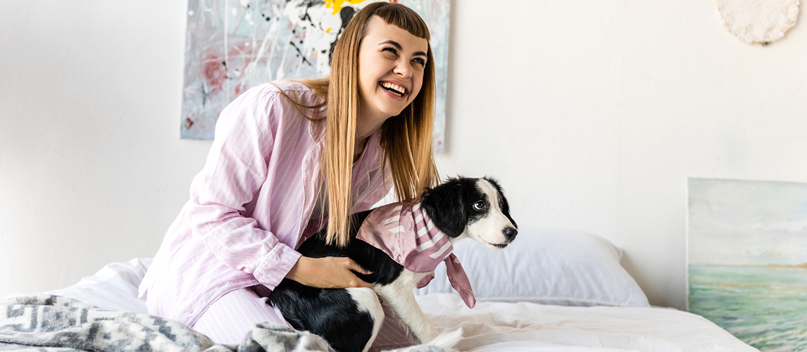 Happy woman in pajamas and cute little puppy resting 