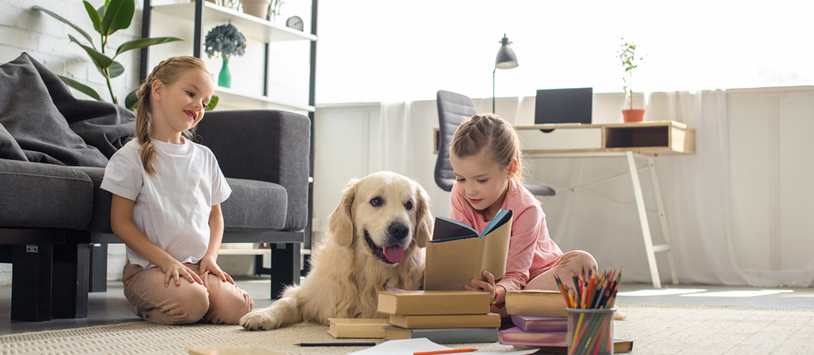 Little sisters reading books with golden retriever dog