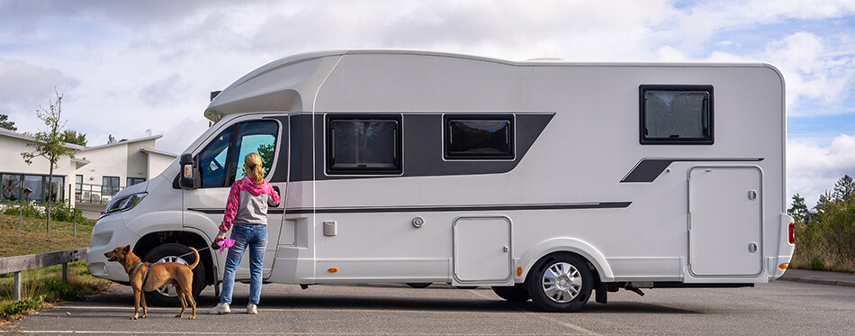 A woman with her dog gets into a car for travelling. House on wheels concept