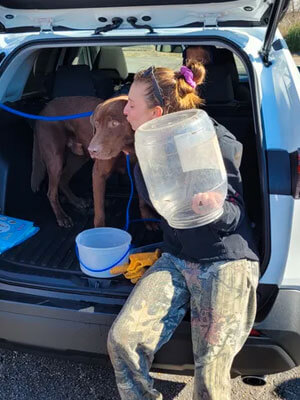 Ashley Smith gives a kiss to the dog she and others searched for and rescued Sunday. His head was stuck in the jug Smith is holding; she tackled him and pulled it free.