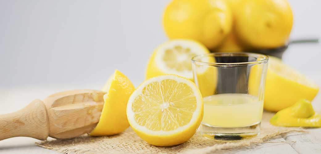 A glass of squeezed lemon juice and lemons around.