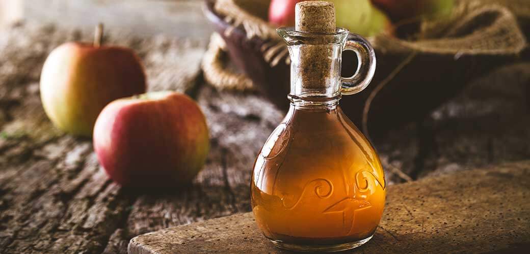 Bottle of apple organic vinegar on wooden background.