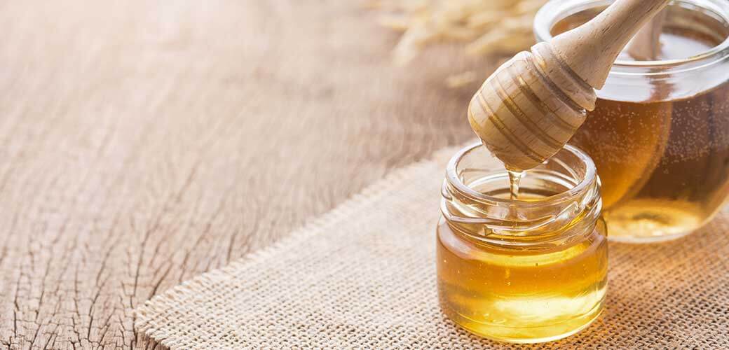 Honey with wooden honey mat on wooden table.